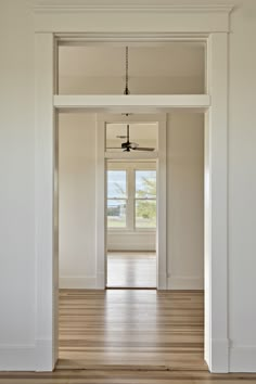 an empty room with white walls and wood flooring is seen from the entrance way