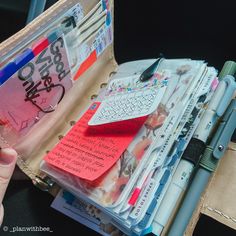 a person holding a wallet full of notes and pens