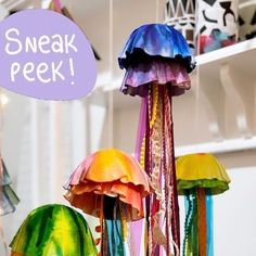 several colorful jellyfishs are hanging from the ceiling with a sign that says sneak peek