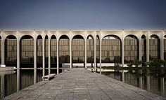 a large building with arches on the side and water reflecting it's reflection in the ground