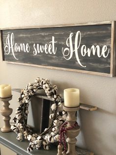 a wooden sign that says home sweet home with candles and wreath on the shelf next to it