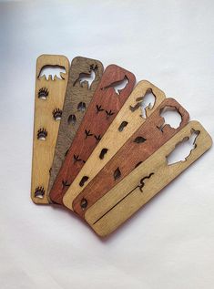 five wooden bottle openers with animals cut out of them on a white table top