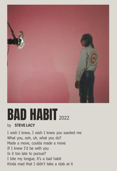 a man standing in front of a pink wall with the words bad habitt written on it