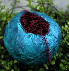 a blue rock with red thread wrapped around it