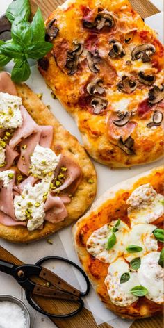 three pizzas with different toppings are on a cutting board next to some scissors