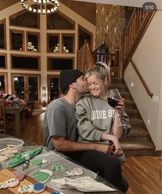 a man and woman sharing a glass of wine in front of some cookies on the table