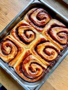 a pan filled with cinnamon rolls on top of a wooden table