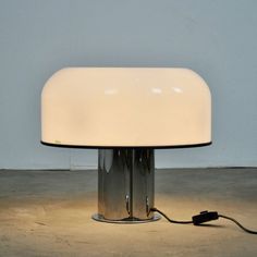 a white table lamp sitting on top of a cement floor