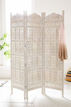 a white room divider sitting on top of a floor next to a potted plant