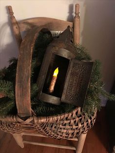 a candle is lit in an old fashioned lantern on a wicker chair with pine branches