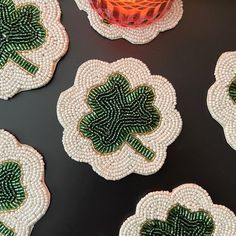 green and white beaded shamrock coasters sitting on top of a black table next to a red vase