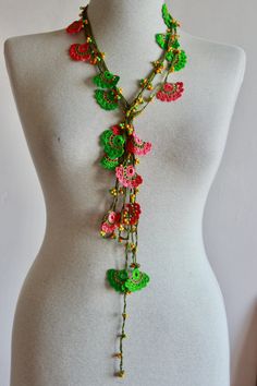 a white mannequin with a green and red necklace on it