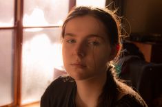 a woman standing in front of a window with sunlight streaming through the window panes