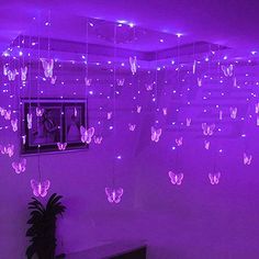 purple butterflies hanging from the ceiling in a room with white walls and lights on it