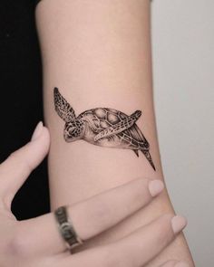 a woman's arm with a turtle tattoo on it