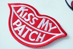 a red patch with the words kiss my match on it's bottom and an image of a heart in the middle