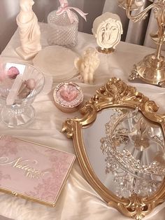 a table topped with lots of glass vases filled with flowers and other items on top of a white cloth covered table