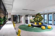 an office lobby with green and yellow furniture in the foreground, large windows to the right