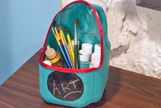 a blue bag with writing on it sitting on top of a wooden table next to a white wall