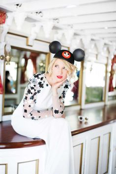 a woman sitting on top of a counter wearing mickey mouse ears