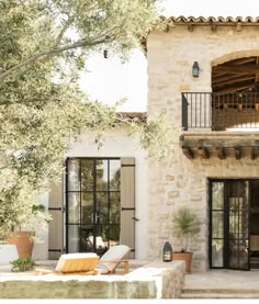 the outside of a house with an outdoor patio and lounge chairs in front of it