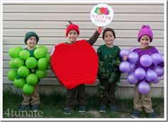 three children dressed up in costumes standing next to each other with green and purple balloons