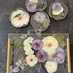 four glass plates with flowers on them sitting on a table next to another plate that has been placed on top of it