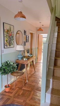 a hallway with wooden floors and pictures on the wall, plants in potted planters