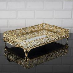 a gold and black tray on top of a glass table next to a brick wall