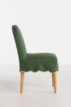 an upholstered green chair with scalloped back and wooden legs, against a white background