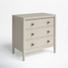 a white dresser with three drawers and two knobs on each drawer, against a white background