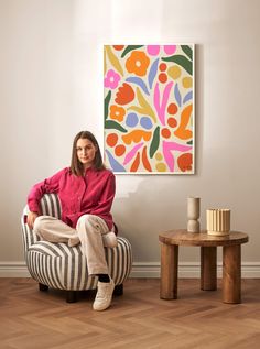 a woman sitting on a chair in front of a painting