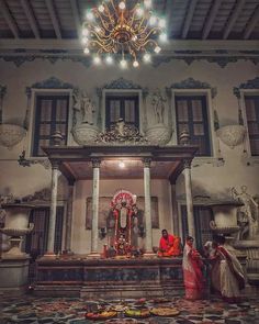 two women are standing in front of a shrine with an ornate chandelier hanging from the ceiling