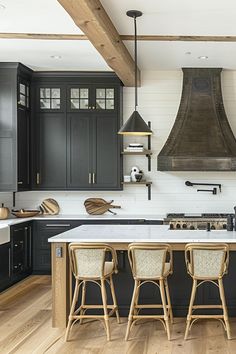 a kitchen with black cabinets and white counter tops, an island in the middle is surrounded by stools