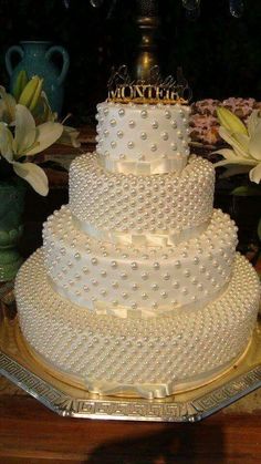 a three tiered wedding cake with pearls on it