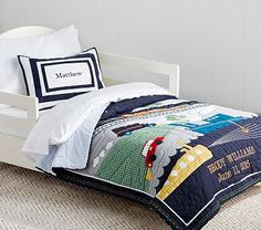 a child's bed with transportation themed comforter and pillows