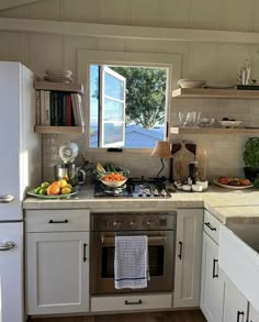 a kitchen with an oven, dishwasher, sink and window overlooking the water