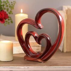 a heart shaped candle holder sitting on top of a table next to a vase with flowers