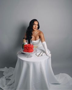 a woman sitting at a table with a red cake