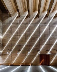 an empty room with wooden walls and beams on the ceiling is lit by sunlight streaming through the windows