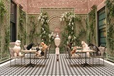 several dogs are sitting at tables in the middle of a room with ivy covered walls