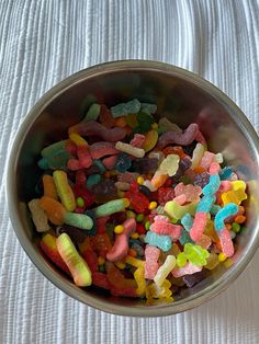 a bowl filled with gummy bears on top of a bed