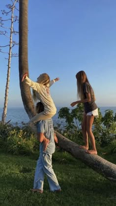 two children playing on a fallen tree near the ocean