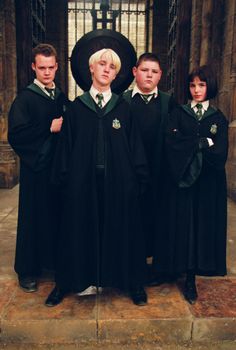 three boys in black robes standing next to each other with their hands on their hips