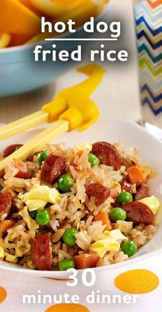 a bowl filled with rice, peas and sausage next to oranges on a table