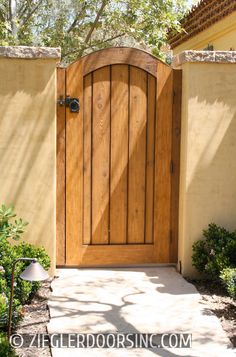 a large wooden door in the side of a house with stone walkway leading to it