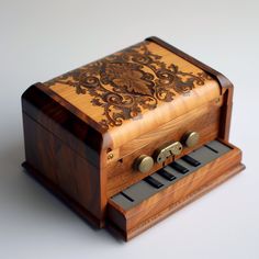 an old fashioned wooden music box sitting on top of a white table with keys in it