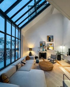 a living room filled with lots of furniture under a skylight next to a fire place