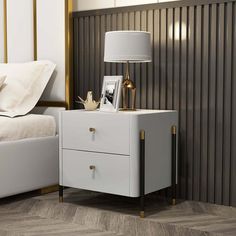 a nightstand with two drawers and a lamp next to it on top of a bed