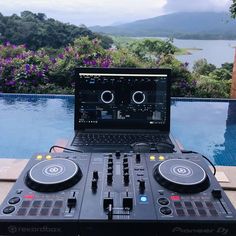 an open laptop computer sitting on top of a dj's desk next to a pool